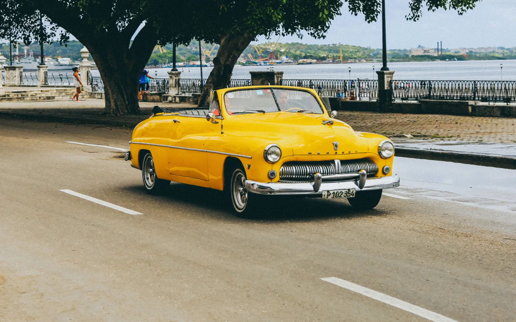 Yellow Mercury Eight convertible driving along the seafront in Havana