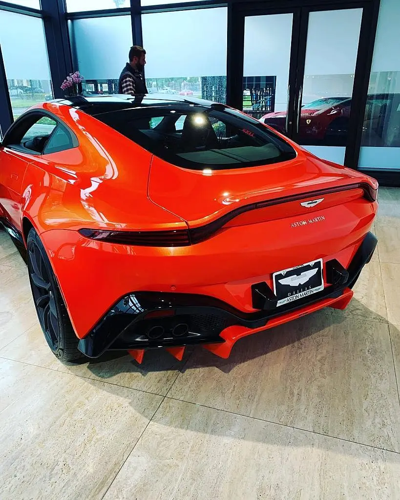 Orange Aston Martin Vantage from behind in a showroom
