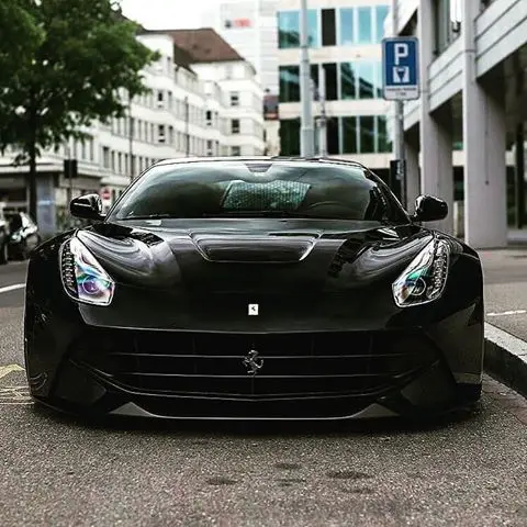 Black Ferrari F12 Berlinetta in front of a car park wall