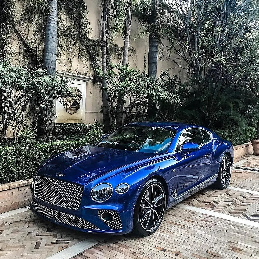 Blue Bentley Continental GT in a tropical garden