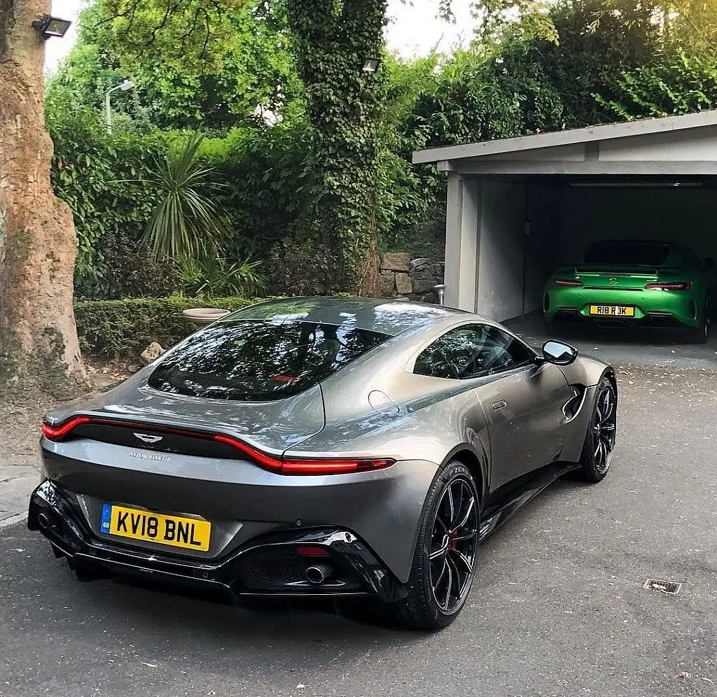 Grey Aston Martin Vantage from behind in front of a garage