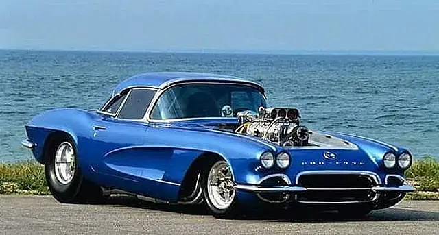 Blue early Corvette with a supercharger by the sea