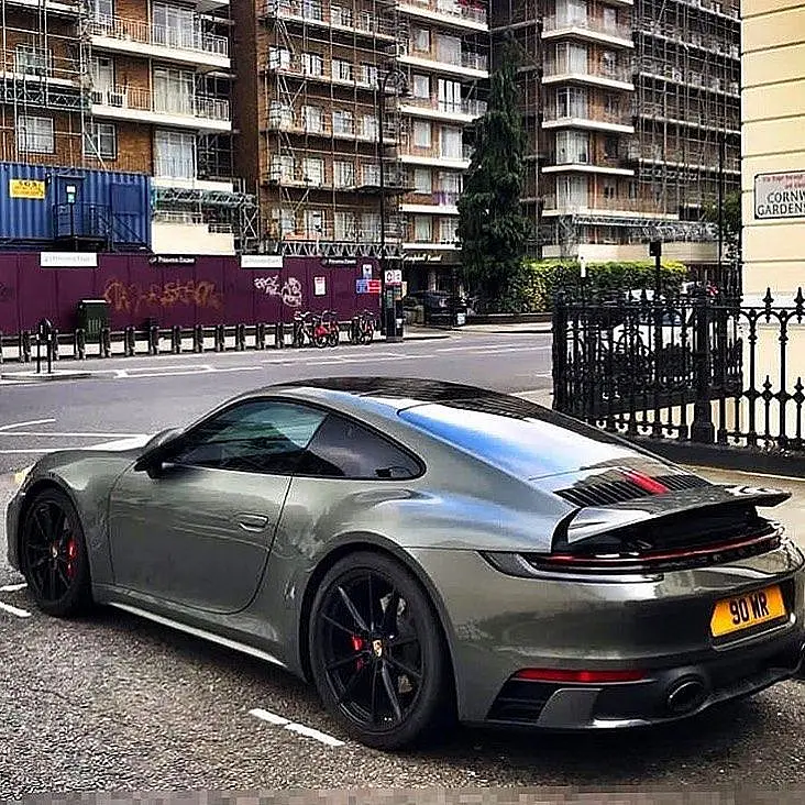 Grey-green Porsche 911 with a yellow plate on a London street