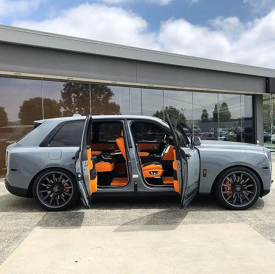 Grey Rolls-Royce Cullinan with its doors open and an orange interior