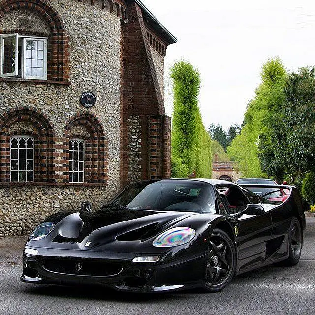 Black Ferrari F50 in front of a stone house
