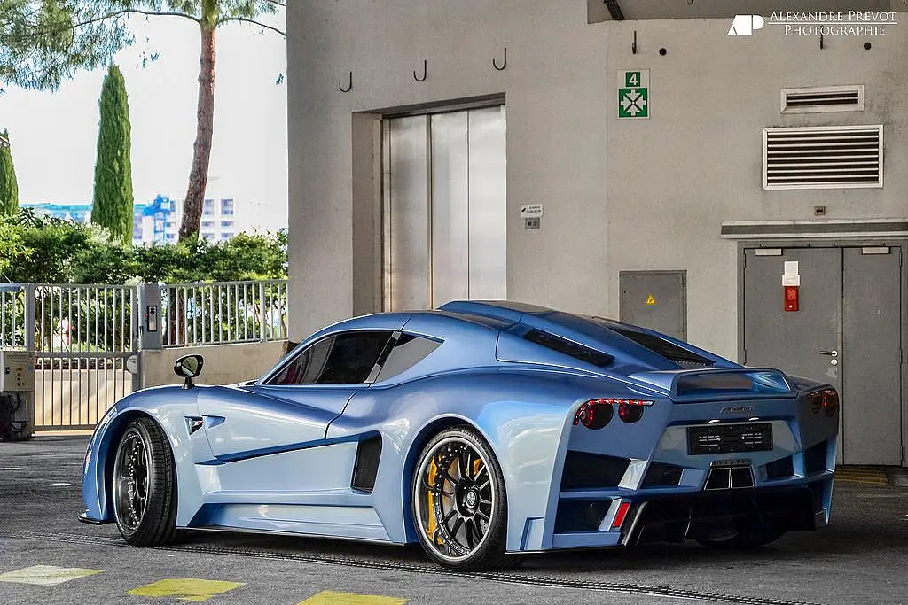 Light blue supercar with gold wheels in a car park
